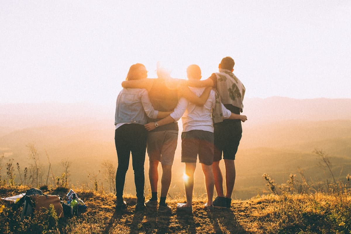 Friends holding each other close in warm light.